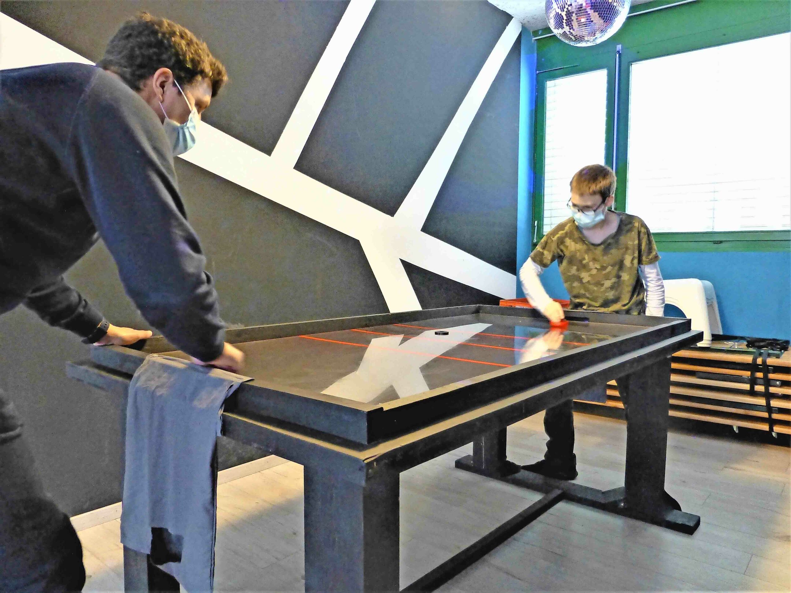 Christoph Steiger spielt mit Dominik (11) am neuen Air-Hockey-Tisch.